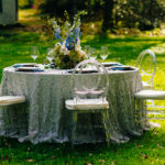 A table set up with flowers and glasses on the grass.