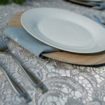 A table set with plates and silverware on lace tablecloth.
