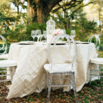 A table set up with white chairs and a tree
