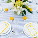 A table set with plates and napkins, lemons on the table.