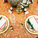 A table set with plates and silverware on top of a red cloth.