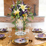 A table set with plates and silverware, napkins and flowers.