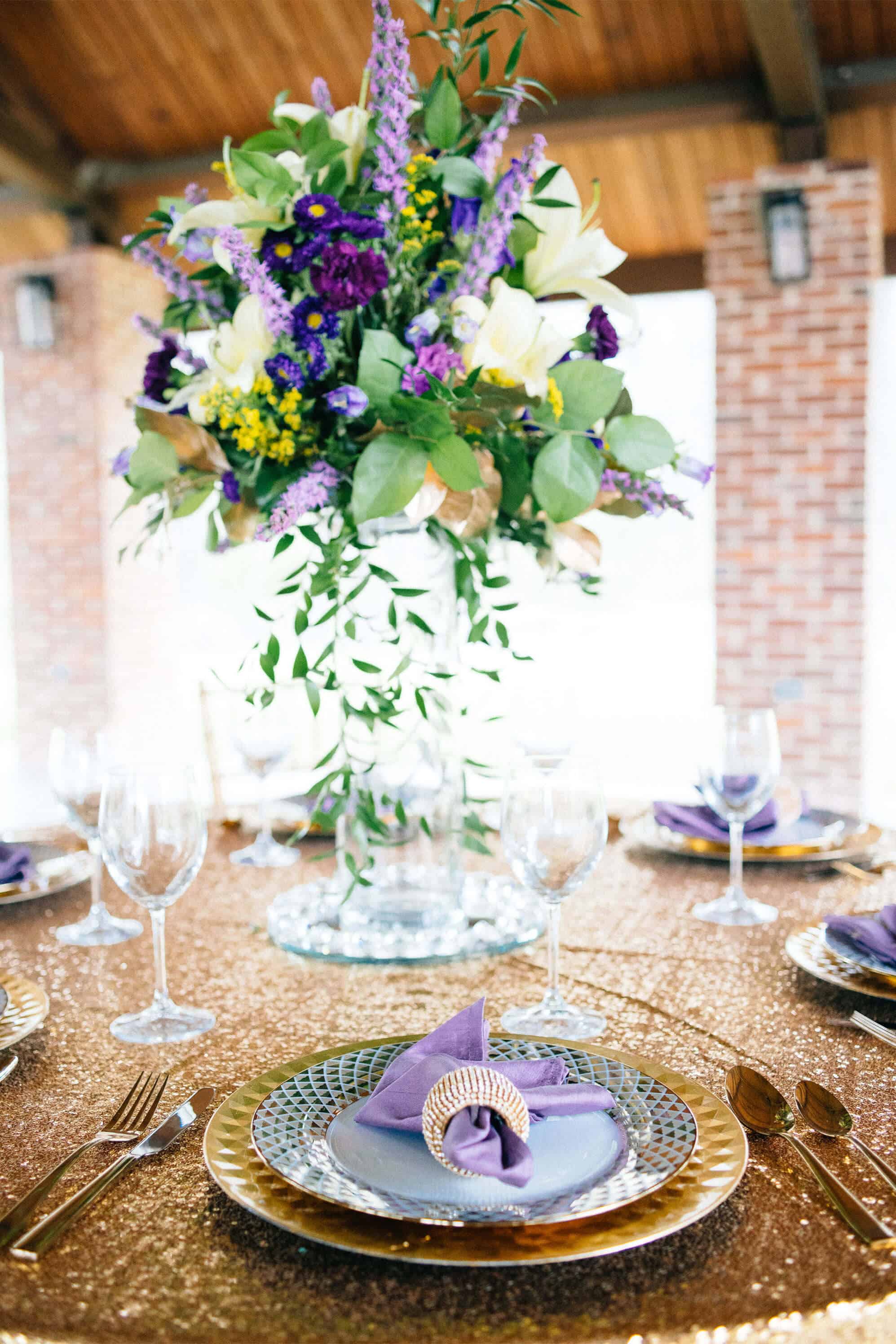 A table set with plates and glasses, and flowers in the center.