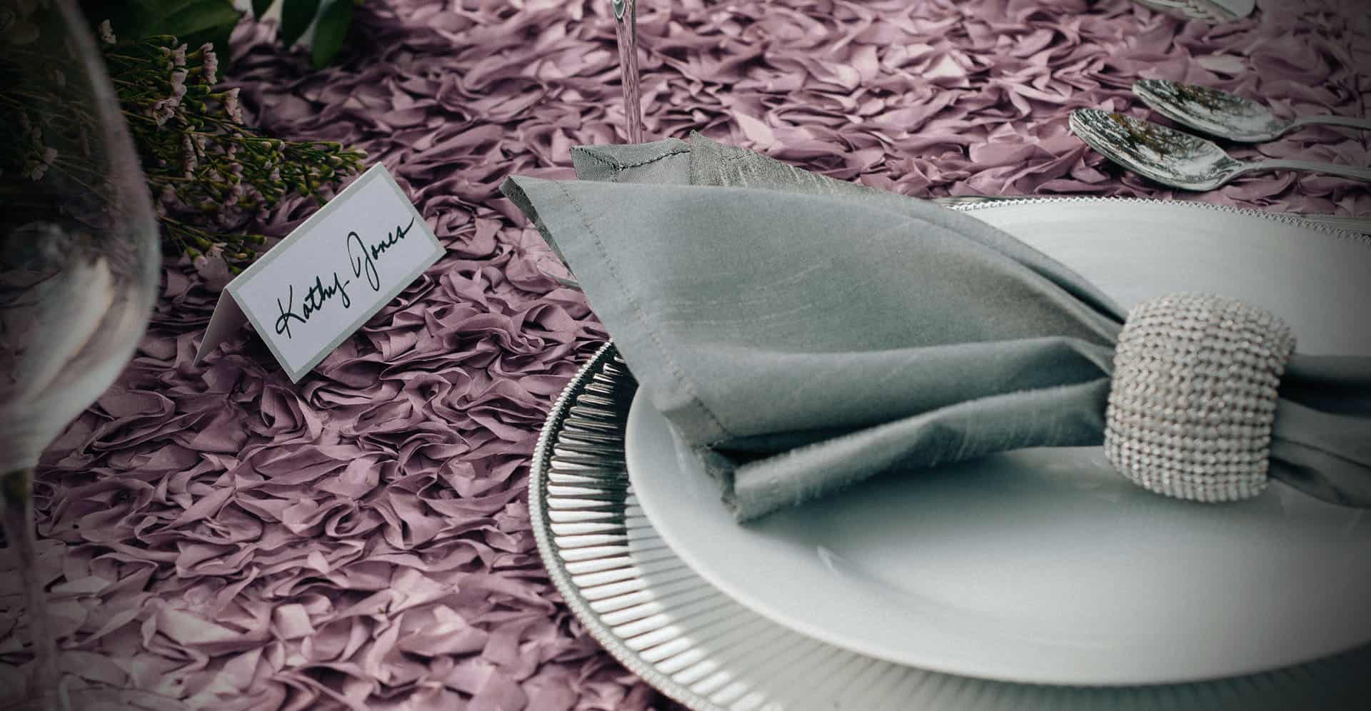 A table set with plates and napkins on top of purple fabric.